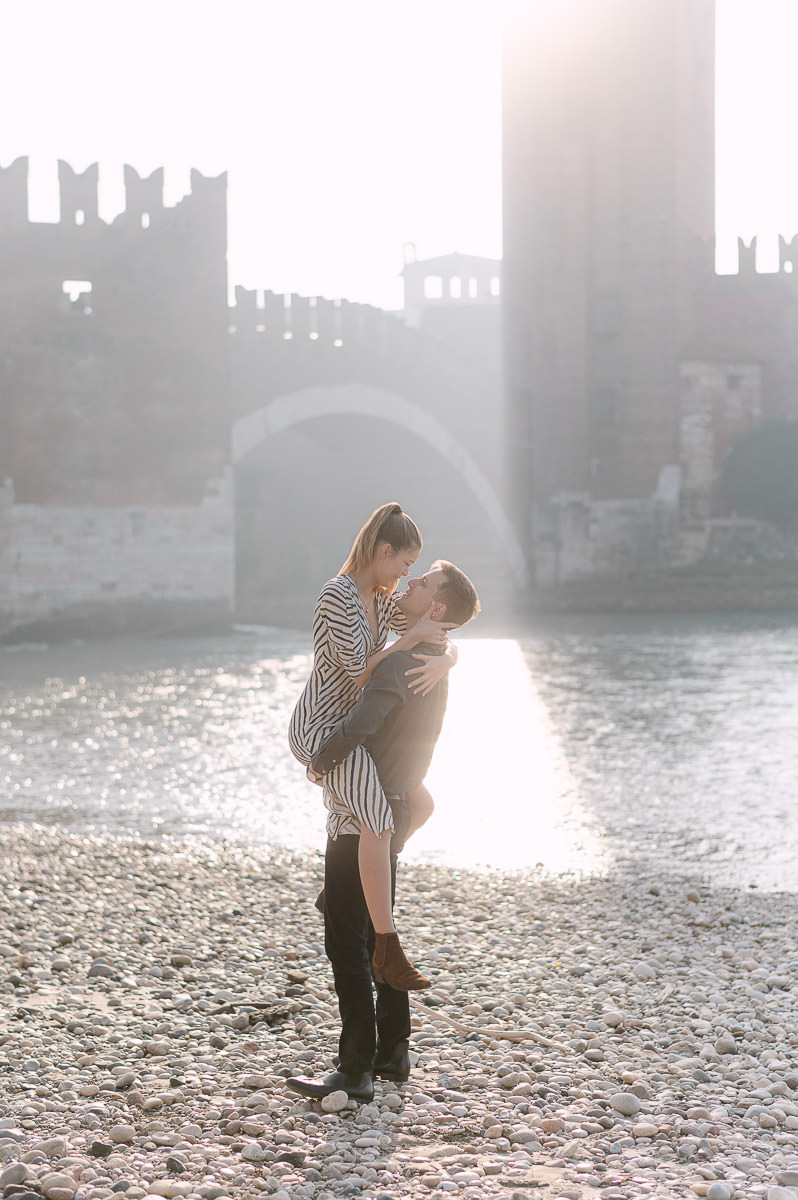 Couple lifting moment after proposal at Castelvecchio bridge