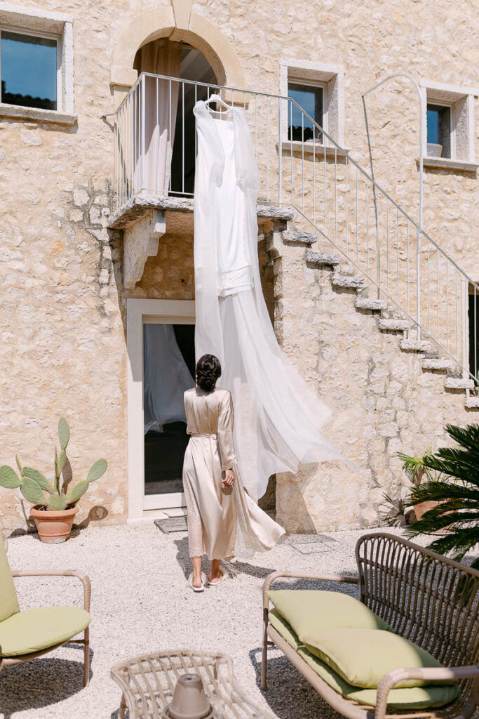 Preparazione della sposa a Villa Mosconi Bertani con abito da sposa appeso nel cortile