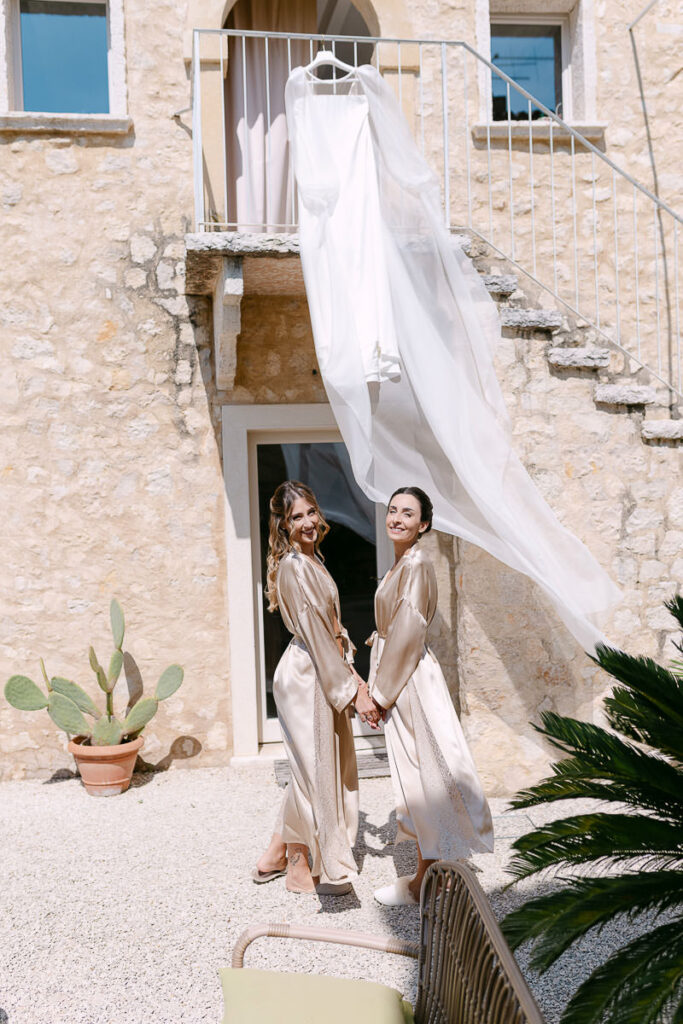 Sposa e damigella durante la preparazione a Villa Mosconi Bertani con abito da sposa nel cortile