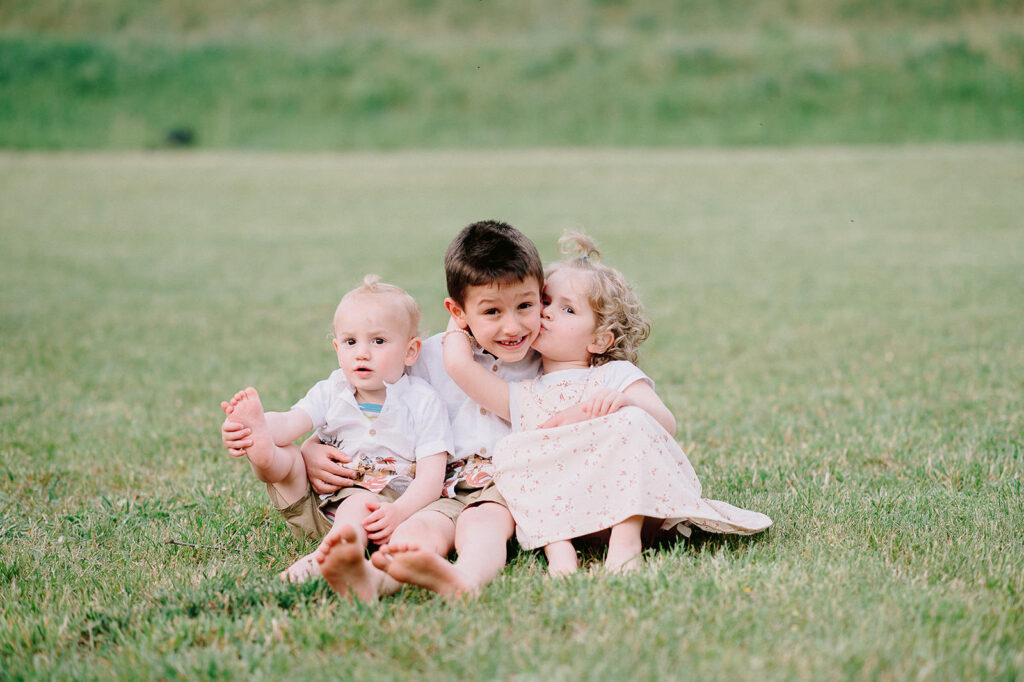 Tre bambini abbracciati e sorridenti durante un servizio fotografico di famiglia a Verona