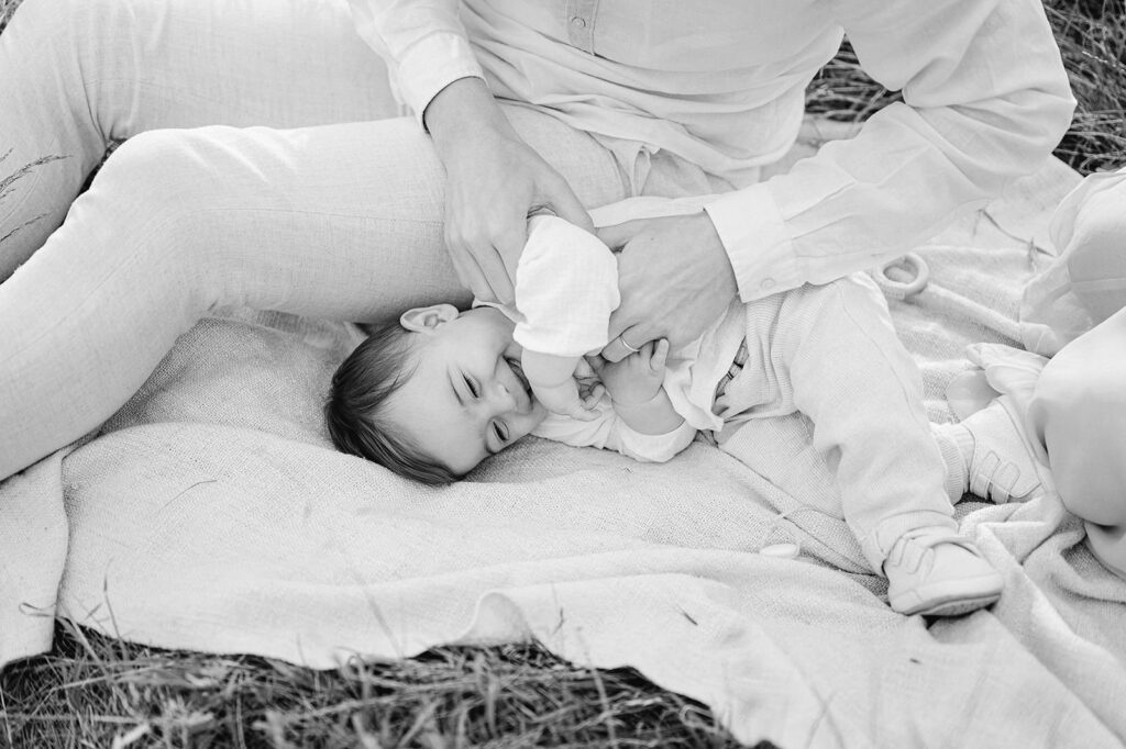 Bambino sdraiato su una coperta mentre gioca durante un servizio fotografico di famiglia all’aperto a Verona