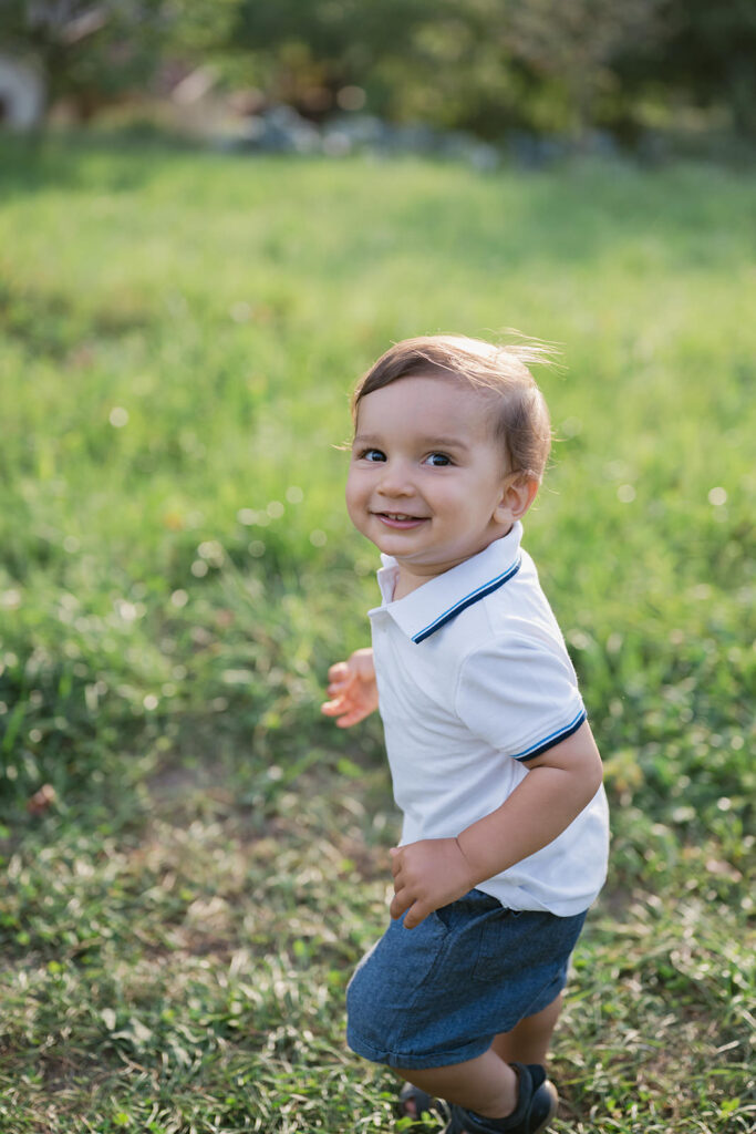 Bambino che cammina sorridendo su un prato durante un servizio fotografico di famiglia a Verona