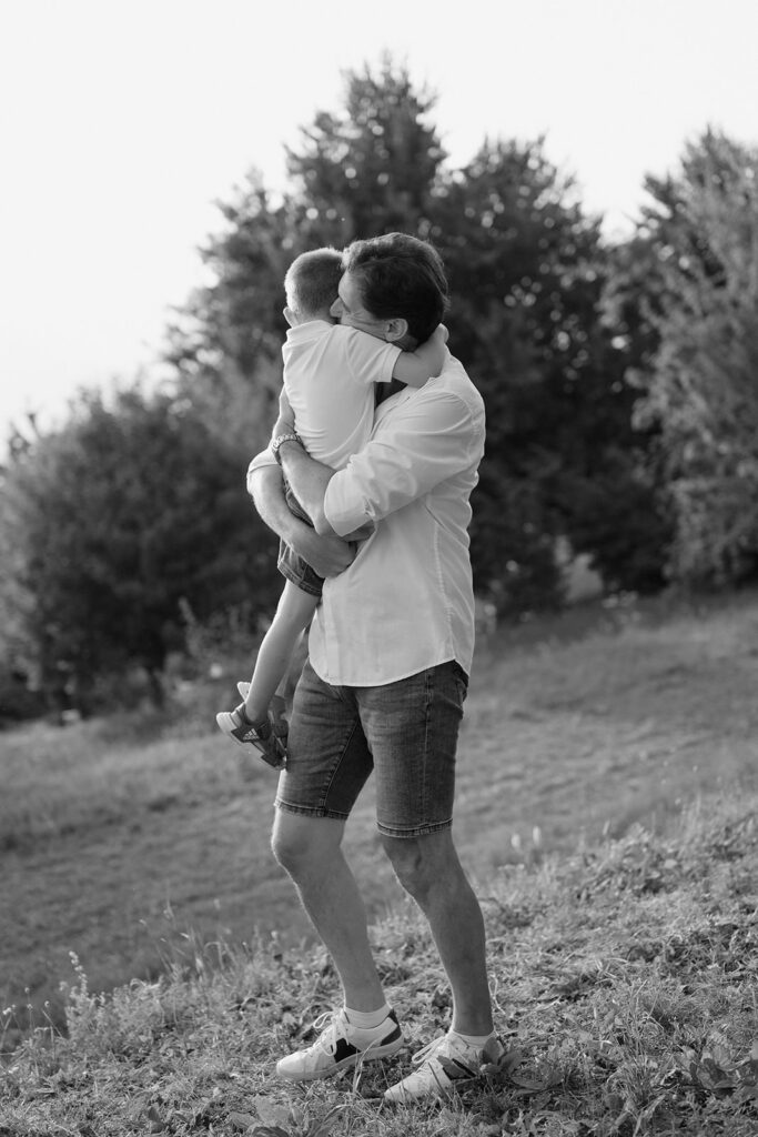 Padre che tiene in braccio il figlio durante una passeggiata in un servizio fotografico di famiglia in bianco e nero a Verona