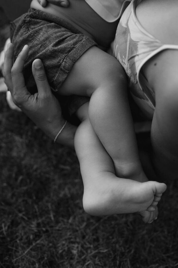 Dettaglio delle gambe di un bambino tra le braccia dei genitori durante un servizio fotografico di famiglia a Verona